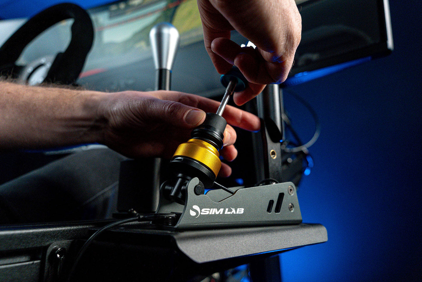 Person adjusting a steering wheel on a Sim Lab simulator