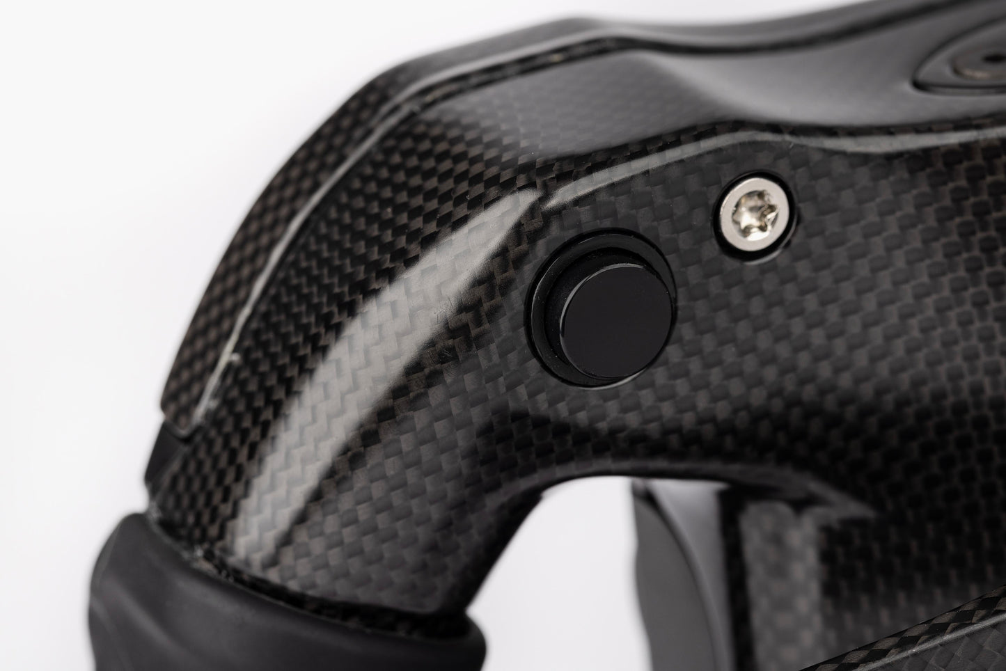 Close-up of a black carbon fiber handle with a button and screw on a white background