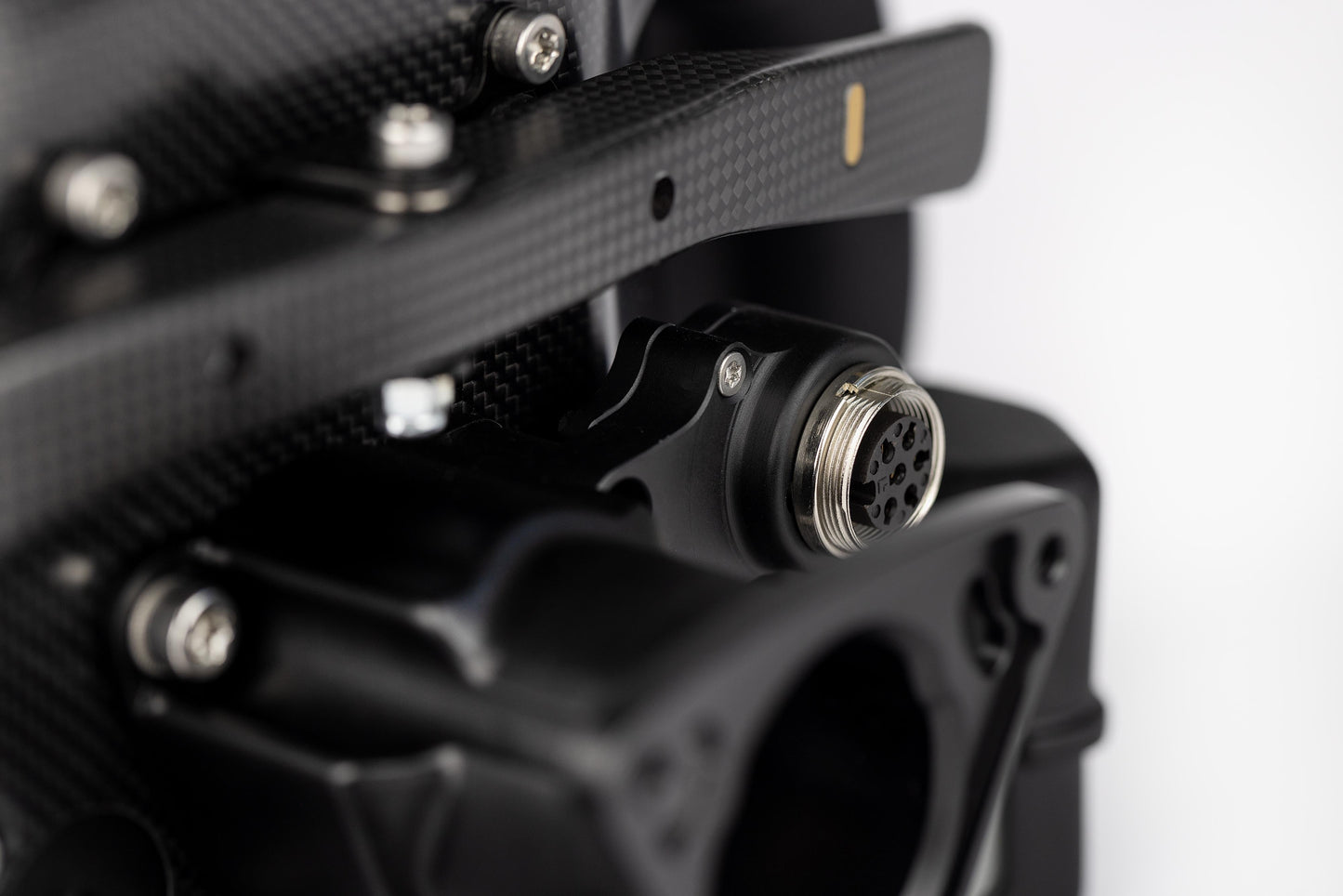 Close-up of a black mechanical component with a metallic connector on a white background