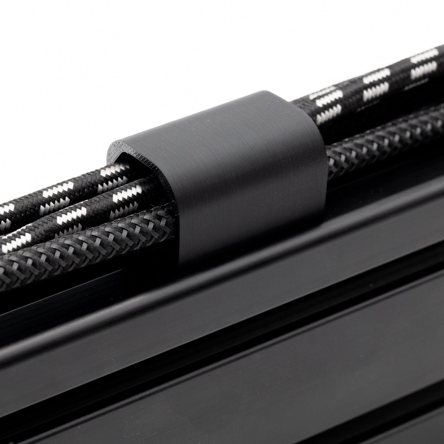 Close-up of black cable ties securing black braided cables on a white background