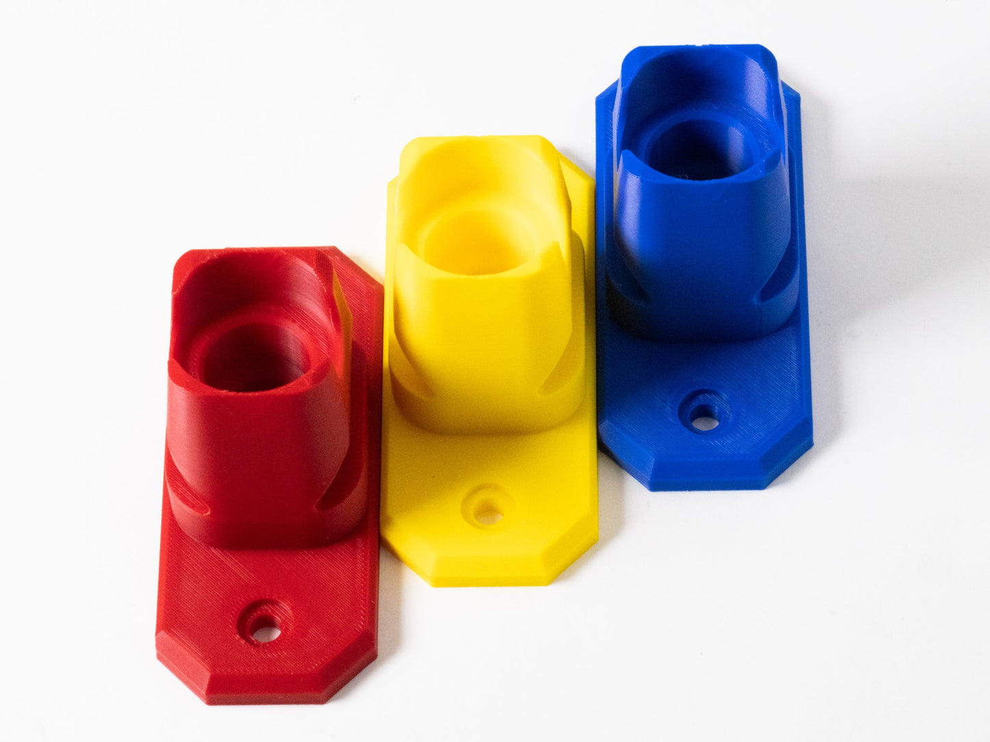 Three colorful plastic blocks in red, yellow, and blue on a white background