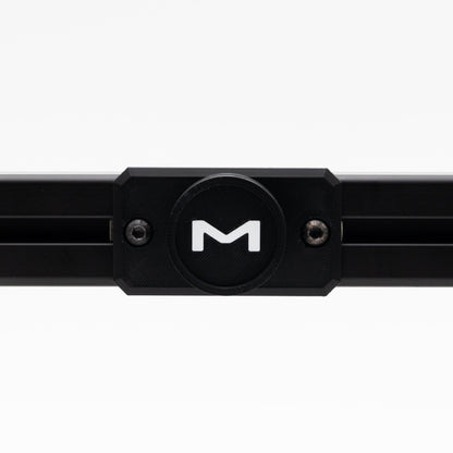 Black metal bar with a circular component featuring a 'M' logo on a white background
