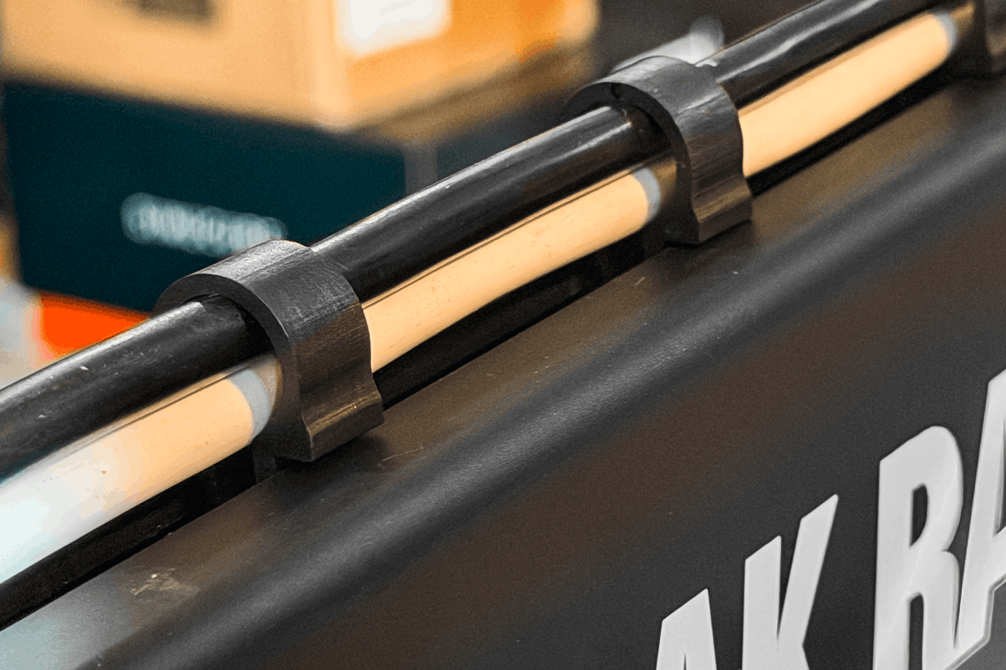 Close-up of a black metal bar with wooden slats on a vehicle, with 'AK Racing' branding.